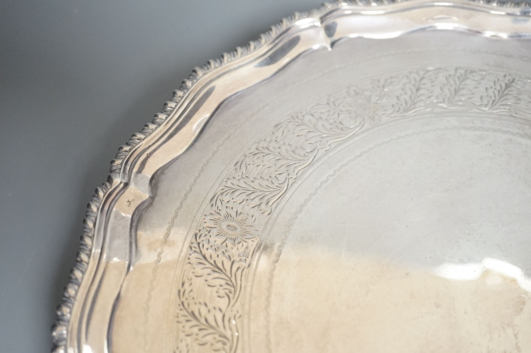 A George III silver salver, with gadrooned border, on three shell feet, Ebenezer Coker, London, 1773, 28.1cm, (repairs), 20.5oz.